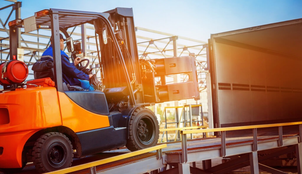 Used Forklifts is putting cargo from warehouse to truck outdoors